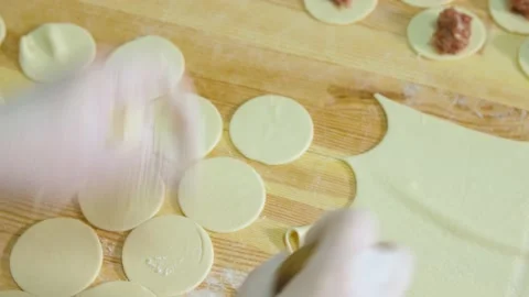 Hands cut out circles of dough for making dumplings, in the production of semi Video stock 163923150