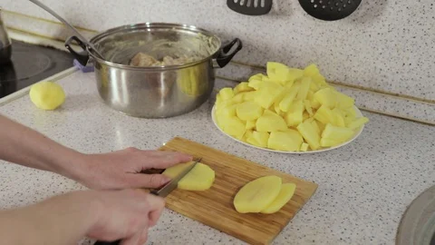 Hands cut potatoes in slices on wooden board Stock Footage 127911036