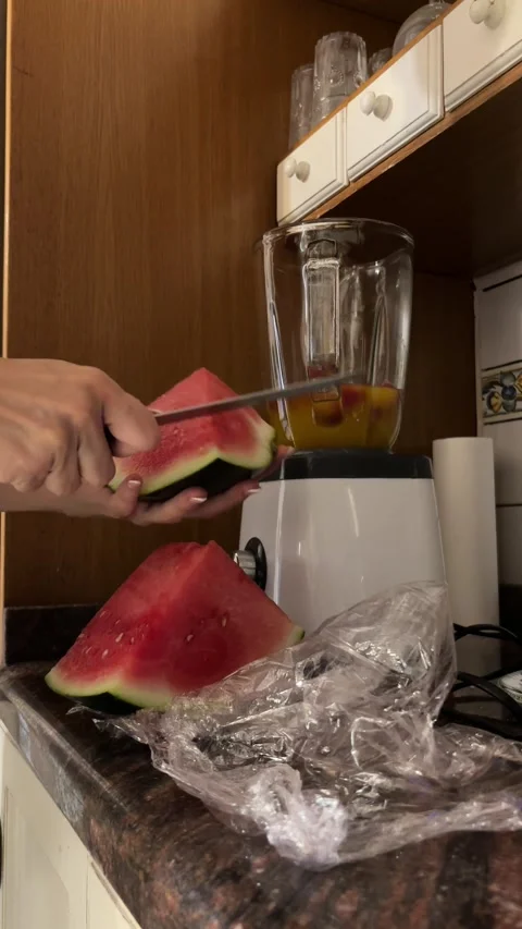 Hands cutting and adding watermelon to blender vertical shot Stock Footage 345661157