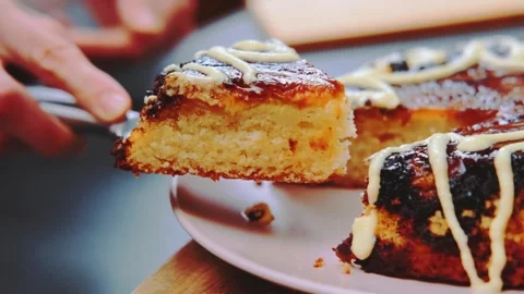 Hands cutting and lifting a piece of glazed chocolate cake indoors Stock Footage 342936522