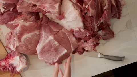 Hands Cutting and Trimming Raw Pork Chunks on Marble Kitchen Counter Stock Footage 343250037