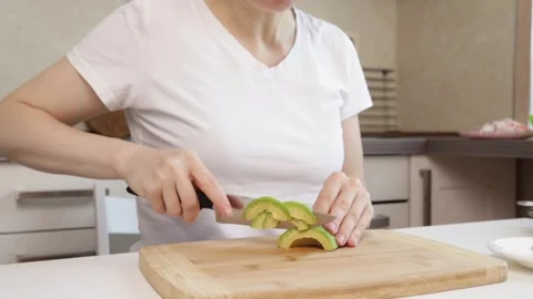 Hands cutting avocado in the kitchen with cooking knife, lunch preparation,.. Stock Footage 305391449