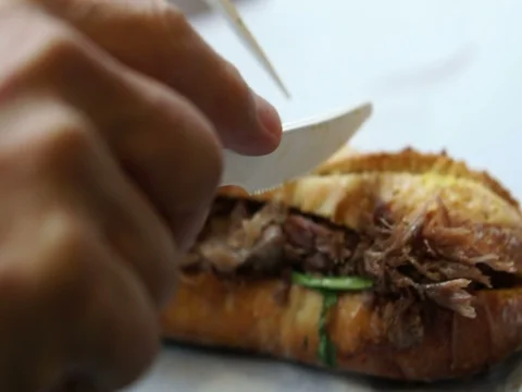Hands cutting baguette filled with pulled duck meat sandwich Stock Footage 79852568