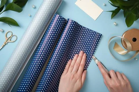 Hands cutting blue polka dot wrapping paper with a craft knife. Ribbon, sci.. Stock Photos
