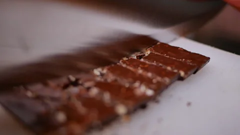 Hands cutting the chocolate into small pieces with knife on cutting board. Stock Footage 158661003
