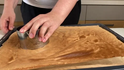 Hands cutting circular pieces from a sponge cake sheet with a round mold to Video stock 317154846