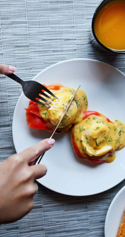 Hands Cutting Eggs Benedict with Smoked Salmon for Breakfast Stock Footage 323944823