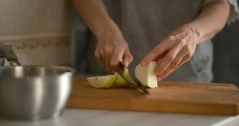 Hands cutting fresh green apple with kitchen knife on wooden board Video stock 338399223