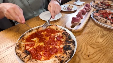 Hands Cutting Fresh Pepperoni Pizza on Wooden Restaurant Table 스톡 동영상 337995192