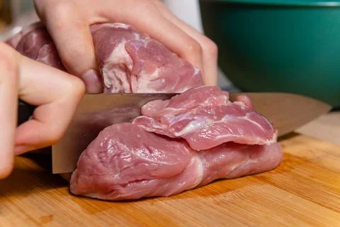 Hands cutting fresh raw meat on wooden board photo Foto stock