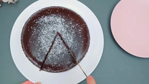 Hands cutting glossy chocolate cake with powdered sugar on white plate indoors 库存影片 342885814