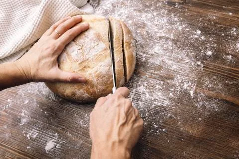 Hands cutting a loaf of rustic bread in slices Stock Photos