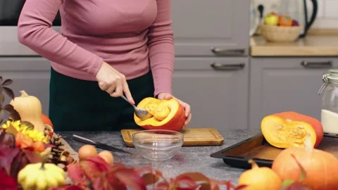 Hands cutting orange ripe raw pumpkin peel remove pumpkin seeds with spoon for Stock Footage 218790669