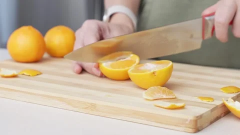 Hands cutting orange tangerines on the cutting board on table, lots of juicy Stock Footage 283515165