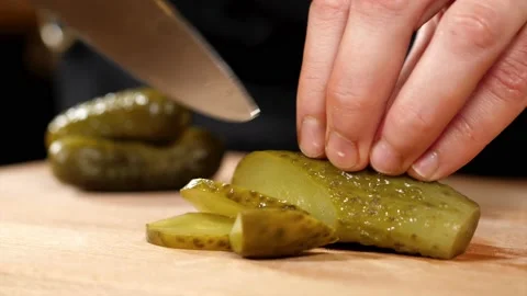 Hands is cutting a pickled cucumber with a knife on wooden board, close-up Stock Footage 144311298