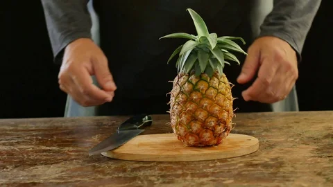 Hands cutting pineapple on a cutting board on a wooden table. Stock Footage 94268757
