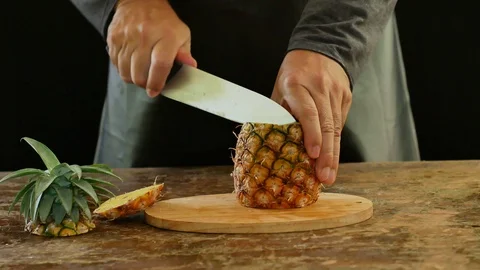 Hands cutting pineapple on a cutting board on a wooden table. Stock Footage 94268780