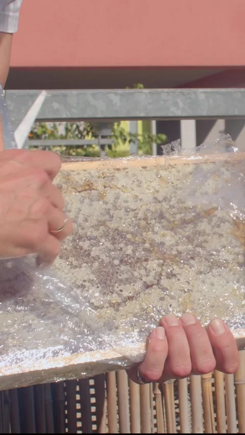 Hands cutting plastic wrap off resin board in bright sunlight Видео 347323121