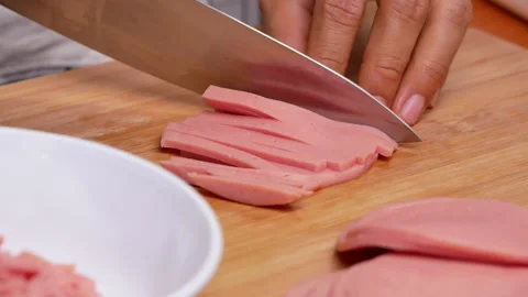 Hands cutting raw ham bologna into dice using a knife on the cutting board. Stock Footage 158658348