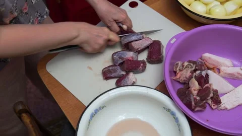 Hands Cutting Raw Meat On Cutting Board In Kitchen With Bowl Of Meat Preparation Video stock 325100750