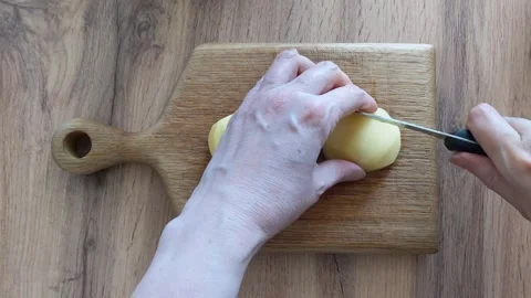 Hands cutting raw potatoes with a sharp knife with a black handle Stock Footage 336279553