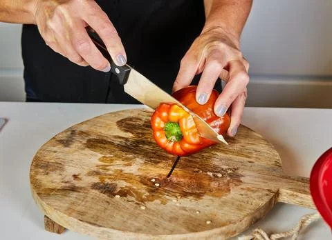 Hands Cutting Red Bell Pepper on Wooden Board Stock Photos