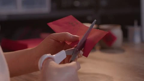 Hands Cutting Red Paper Envelope with Scissors on Wooden Table Stock Footage 336546724
