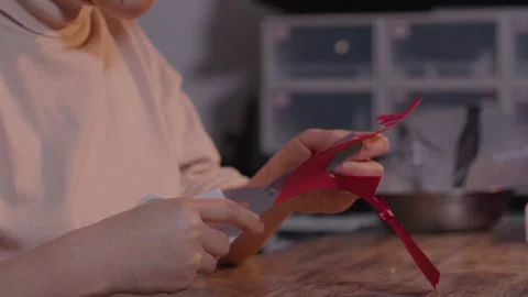 Hands Cutting Red Paper with Scissors on Wooden Table, Close-up Stock Footage 336546620