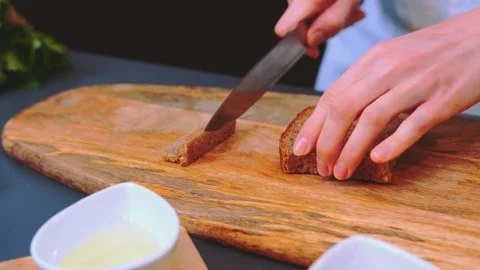 Hands cutting rye bread into croutons on wooden cutting board indoors 스톡 동영상 342856029
