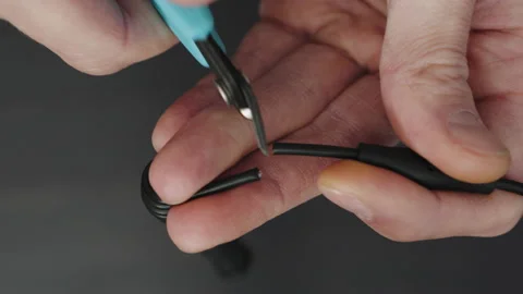 Hands cutting wire on wooden table in close-up Stock Footage 235911451