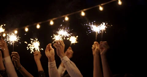 Hands in the dark waving sparklers . on backdrop of garland. new year, holiday Stock Footage 121376376