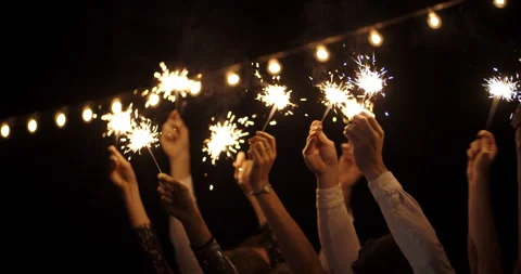 Hands in the dark waving sparklers . on backdrop of garland. new year, holiday Stock Footage 220631432
