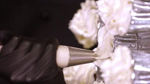 Hands decorating a batch of cakes on a tray with whipped cream, vertical video Stock Footage 297624182