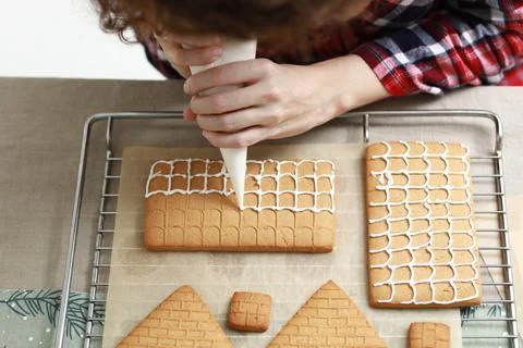 Hands decorating christmas gingerbread cookies with icing on table with candl Stock Photos