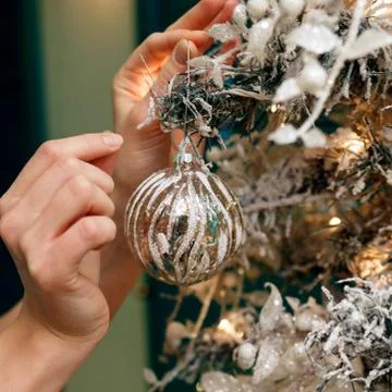 Hands decorating christmas tree with a silver balls. Stock Photos