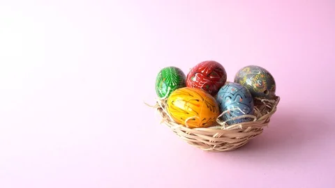 Hands decorating modern painted easter eggs on pink table Stock Footage 125360661