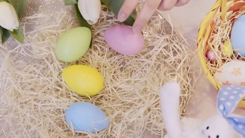 Hands decorating table with dyed Easter eggs on floral Easter background. Stock Footage 236341766