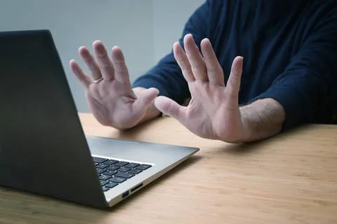 Hands in defensive gesture against a laptop computer, avoiding further wor... Stock Photos