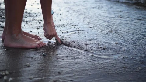 Hands delicately trace heart on the soft sand near the water, creating a simple Stock Footage 282698452