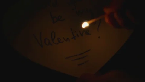 Hands demonstrate in darkness with fire of match what is written on heart shaped Vidéo 126262516