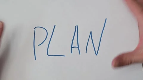 Hands demonstrate folding a piece of paper that starts with the word PLAN Stock-Footage 337550842