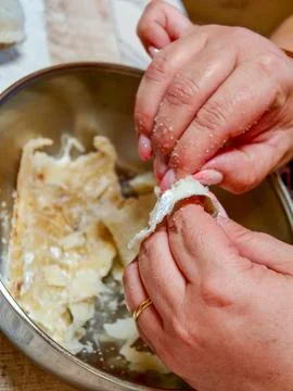 Hands deshelling salted cod for traditional cooking Photos