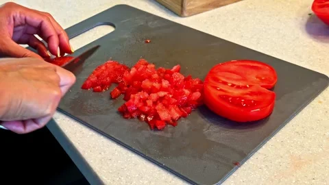 Hands Dicing Tomato on Cutting Board for Meal Preparation in Home Kitchen Stock Footage 337386345