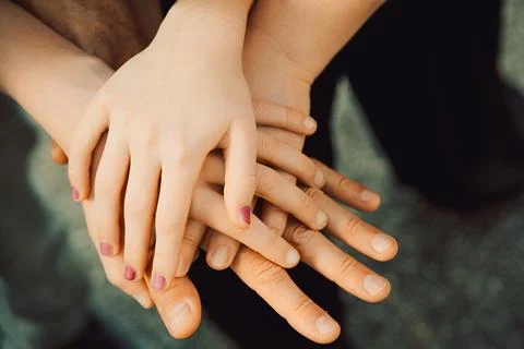 Hands  different sizes stacked together in  supportive gesture in casual outd Stock-Fotos