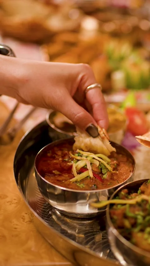 Hands Dipping Naan Bread into Traditional Indian Curry Thali Video stock 337875355