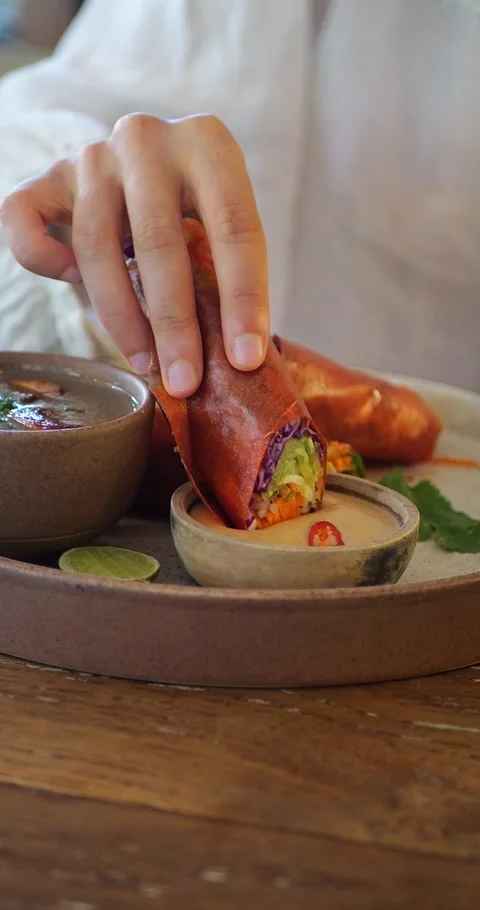 Hands Dipping Papaya Spring Roll Into Sesame Sauce, 4K, Vertical Stock Footage 286428160