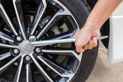 Hands disassembling a modern car wheel (steel rim) with a lug wrench Stock-Fotos