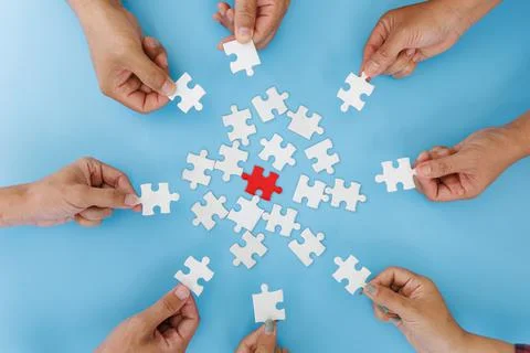 Hands of diverse people assembling jigsaw puzzle, team put pieces together se Stock Photos