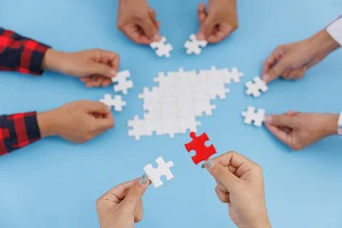 Hands of diverse people assembling jigsaw puzzle, team put pieces together se Stock Photos