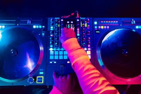 Hands of a DJ creating and regulating music on dj console mixer at club concert Stock Photos